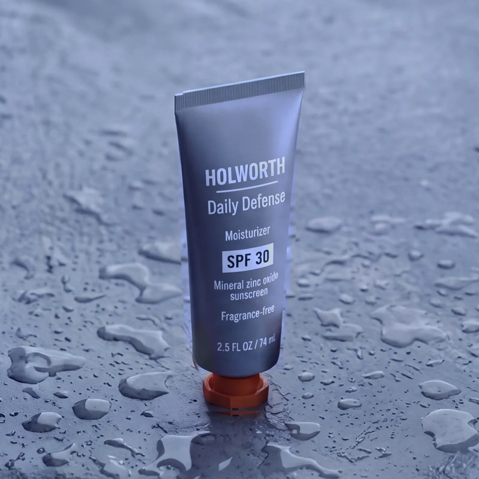 Holworth Daily Defense Moisturizer SPF 30, a slate-grey container with an orange cap, labeled HOLWORTH, on grey concrete.